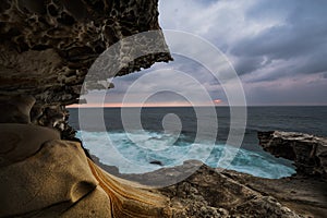 Gloomy cliffs with arch projection and ocean