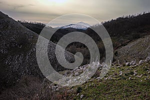 Gloomy landscape of rocks, woods and winter Etna Mount from Nebrodi Park