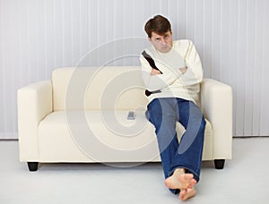 A gloomy man sitting on couch in front of TV
