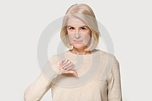 Gloomy mature woman looking at camera showing thumbs down