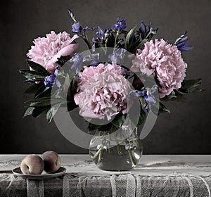 Gloomy still life with flowers and fruit in a dark key.