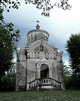 Gloomy view of the Sainte-Beatrix chapel against a dark evening sky with heavy rain clouds photo
