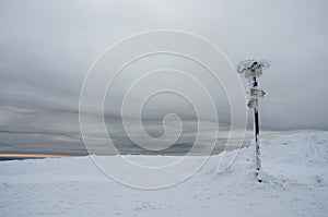 Gloomy winter landscape with frozen sign showing directions