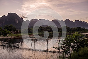 Glorious sunset over the mountains that dominate Vang Vieng overlooking the Nam Song river and the wooden bridge, Laos