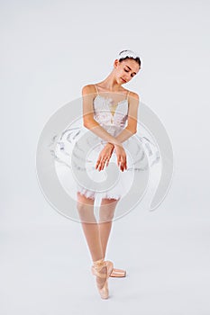 Glory, dream, choreography concept. Slender figure of female ballet dancer in the studio lights wearing beautiful tutu from swan