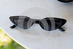Glossy black cat-eye sunglasses with dark lenses placed on light surface