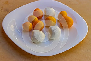 Glossy plate with yellow tomatoes and mozzarella balls