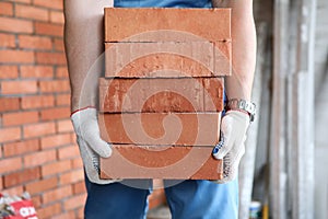 Gloved builder manually carries brick construction