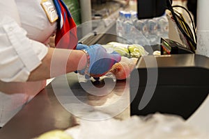 A gloved cashier in a supermarket scans the item. Close-up