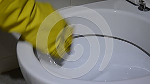 A gloved cleaner washes the toilet