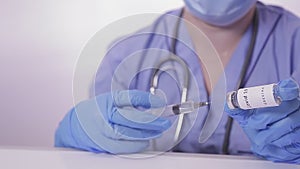 A gloved doctor fills a syringe with a vaccine against the virus