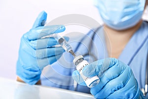 A gloved doctor fills a syringe with a vaccine to prevent the virus.