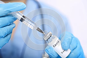 A gloved doctor fills a syringe with a vaccine to prevent the virus