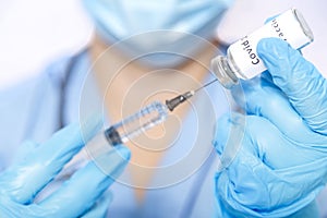 A gloved doctor fills a syringe with a virus vaccine