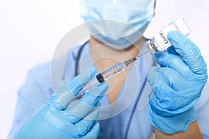 A gloved doctor fills a syringe with a virus vaccine