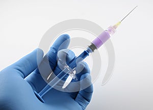 Gloved hand with blue syringe