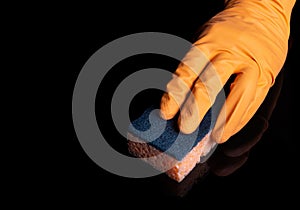 A gloved hand cleans a black table with a pink napkin. Close-up shot of home cleaning process. Healthcare during coronavirus and
