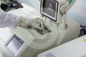 Gloved hand entering sample in lab device