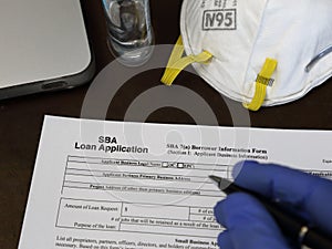 Gloved Hand Filling Out a Small Business Administration SBA Loan Form photo