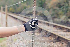 Gloved hand grabbing a fence by railway