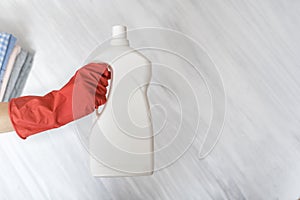 Gloved hand holding a big white bottle. Washing concept