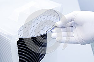 Gloved Hand Holding a Silicon Wafer in plastic holder box used in electronics for the fabrication of integrated circuits