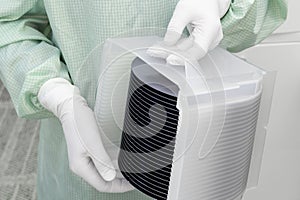 Gloved Hand Holding a Silicon Wafer in plastic holder box used in electronics for the fabrication of integrated circuits