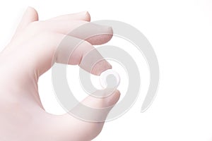 Gloved hand holding small round pill