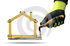 Gloved Hand Holding a Trowel and Folding Ruler in the Shape of House