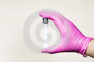 gloved hand holds closed test-tube over desk