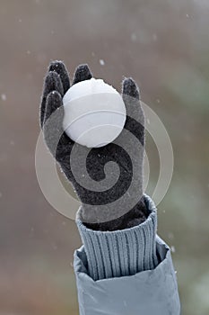 a gloved hand holds a snowball high