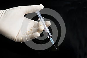 Gloved Hand Holds Syringe On Black