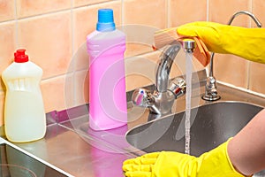 gloved hand with a rag and cleaning products in the kitchen during