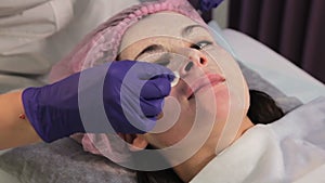 A gloved hand removes the mask from the woman`s face. Reddened, irritated skin after mesotherapy. Close-up