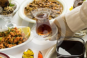 Gloved hand serving Turkish Tea on the Ramadan Dinner Table.