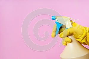 Gloved hand sprays out of a spray bottle on a pink background, copy space, mock up