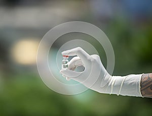 A gloved hand with a vaccine vial