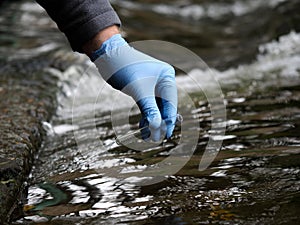 Gloved hand into the water collecting tube. Analysis of water purity, environment, ecology - concept. Water testing