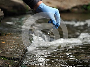 Gloved hand into the water collecting tube. Analysis of water purity, environment, ecology - concept. Water testing