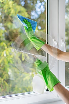 Gloved hands cleaning window glass with detergent