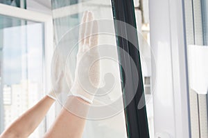 Gloved hands of a craftsman install glass in a plastic window frame