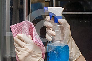 Gloved hands hold a rag and detergent. They wash the glass door of the shower stall. Close-up, horizontal photo The idea is to