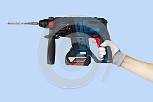 Gloved hands holding drill, perforator construction tools. Work tools on blue background