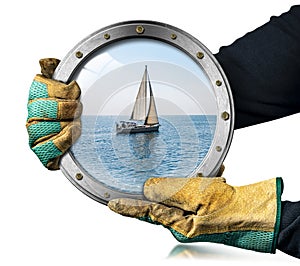 Gloved Hands Holding a Metal Porthole with a Sailing Boat