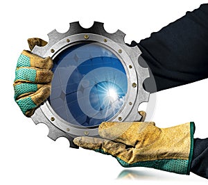 Gloved Hands Holding a Metallic Cogwheel with a Solar Panel Inside