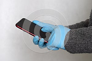 Gloved hands are holding the phone. hands in nitrile gloves. Protective medical gloves