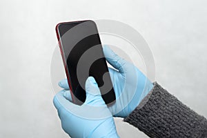 Gloved hands are holding the phone. hands in nitrile gloves. Protective medical gloves