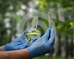 Gloved hands holding retort with a transparent liquid and the tube