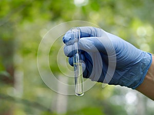 Gloved hands holding a test tube of clear liquid