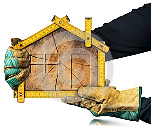 Gloved Hands Holding a Wooden Folding Ruler in the Shape of a House